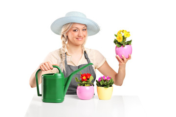 Smiling female gardener posing with flower pots and watering can