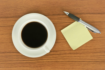 Yellow sticker note and a cup of coffee with pen
