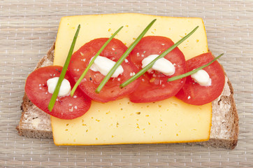 studio-shot of a slice of bread with cheese, tomatoes and chives