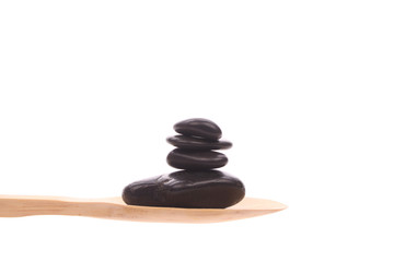 Massage-stones on a wooden spoon isolated on a white background