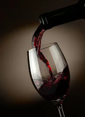 Fotobehang Red wine pouring in glass over dark background © SJ Travel Footage