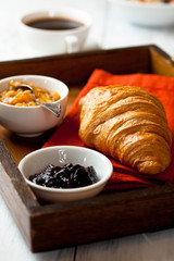 Croissant and fruit jams on a rustic tray