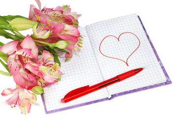 notebook with a pen by flowers and heart