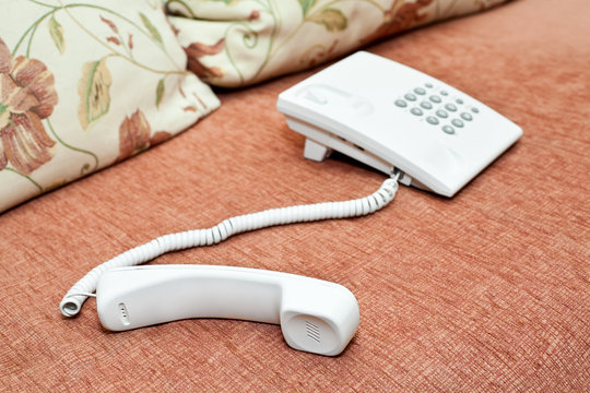 White telephone on sofa. Handset and phonebox