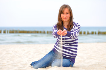 młoda kobieta sypiąca piasek na plaży