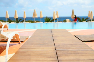 Luxury swimming pool with white deckchairs and white sunshade