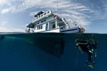 Fototapeten boat and scuba divers over under shot,half underwater © JonMilnes