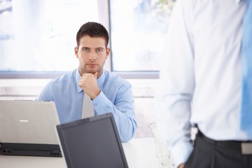 Young businessman working on laptop thinking