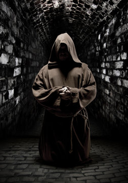 Praying monk in dark temple corridor