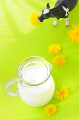 Obraz na płótnie Canvas A cow and a milk jug against a bright green background