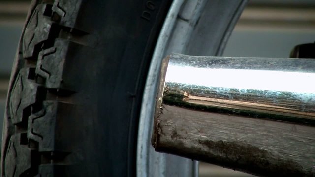 ruota di moto con marmitta fumante e inquinante