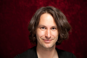 Lächelnder junger Mann mit langem braunen Haar schwarzem shirt