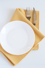 Fork, knife, yellow cloth and white plate