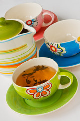 Colorful ceramic cup with tea and teapot