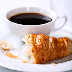 Closeup of croissant and a cup of black coffee