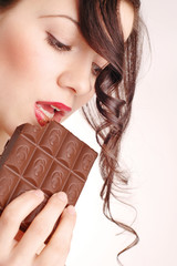 Young beautiful woman eating chocolate bar