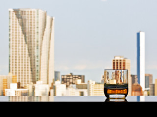 A glass of whisky with panoramic city view on background