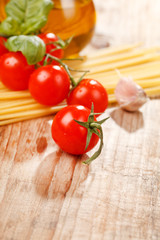 pasta, olive oil and tomatoes on the wood background