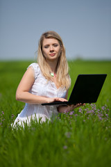 Young blonde woman working with laptop outdoor