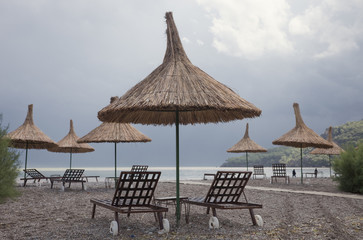 Straw Umbrellas with Sun Loungers on Beach
