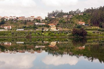 Fototapeta na wymiar Landscape of a small village with its reflection in the river