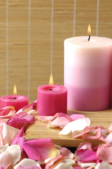 Obraz na płótnie Canvas candle with colorful petals on woven background