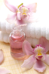 Obraz na płótnie Canvas Pink orchid on spa towel and perfume bottles on straw napkin