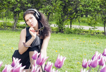 Pretty dreaming brunette with neadphone among flowers