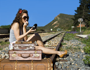 Young traveling woman with her suitcases on the railway tracks