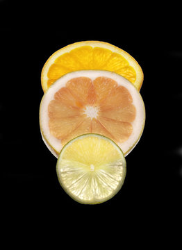 slices of orange, lime and grapefruit isolated on black