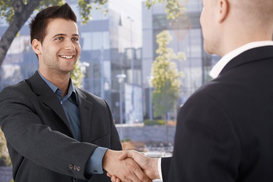 Businessmen shaking hands in front of office