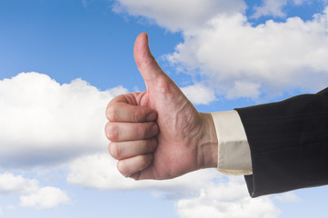 Thumb up and the cloudy sky
