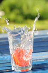 Tomatenscheibe fällt in Wasserglas