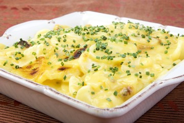 Scalloped potatoes in square ceramic dish