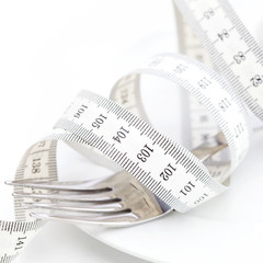 fork and measure tape on a plate isolated on white