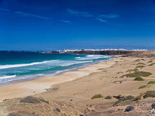 Ocean, sand and  small white town an the rocky shore