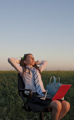 Teen girl sitting with a laptop at field