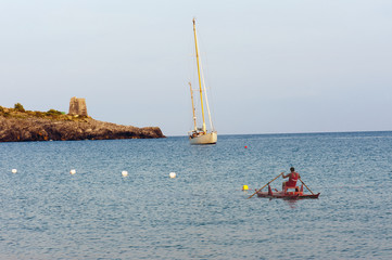 Seascape with a sailboat and a lifeguard rowing at sunset,