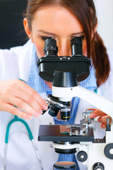 Woman researcher using microscope in laboratory. Close-up.