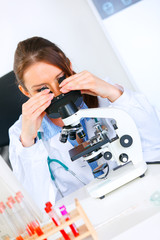 Fototapeta premium Woman researcher using microscope in laboratory. Close-up.