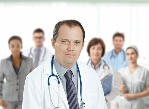 Confident male doctor in front of medical team