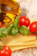 pasta, olive oil and tomatoes on the wood background
