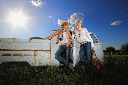 A young couple on a old car in a field