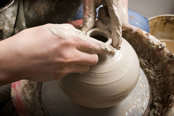 The hands of a potter, creating an earthen jar on the circle