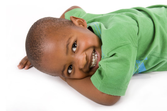 Adorable black boy with a smile laying on the floor