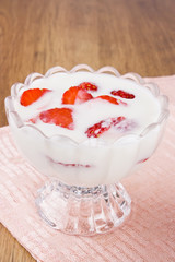Fresh yogurt with strawberry slices in glass bowl