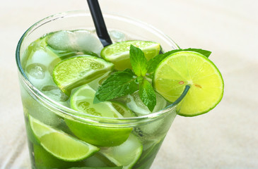 Mojito with rum, limes, mint and ice cubes on sand
