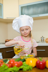 Little girl with oil preparing healthy food on kitchen