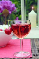 Glas Rotwein mit Kirschen