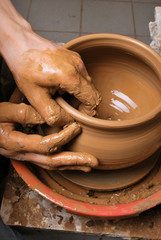 hands of a potter, creating an earthen jar on the circle